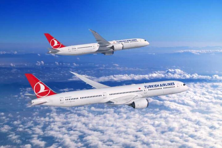 A Boeing 787 Dreamliner in Turkish Airlines livery flying above clouds, showcasing the aircraft's distinctive swept wings and advanced aerodynamic design.