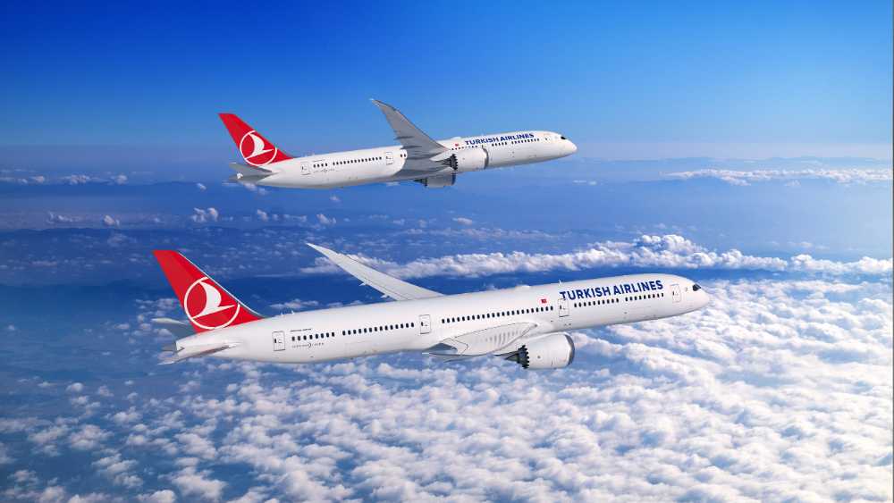 A Boeing 787 Dreamliner in Turkish Airlines livery flying above clouds, showcasing the aircraft's distinctive swept wings and advanced aerodynamic design.