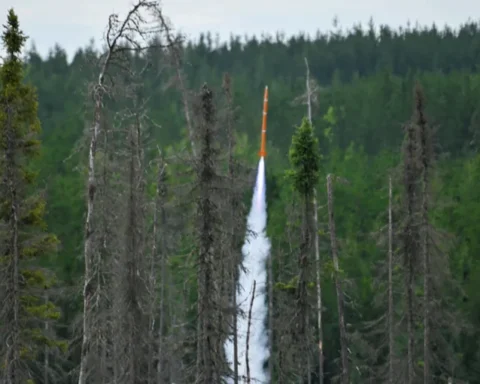 Orange Spectre rocket launched by Turner Fenton Secondary School students streaking upward through a forest clearing at Launch Canada 2025 in Timmins, Ontario.