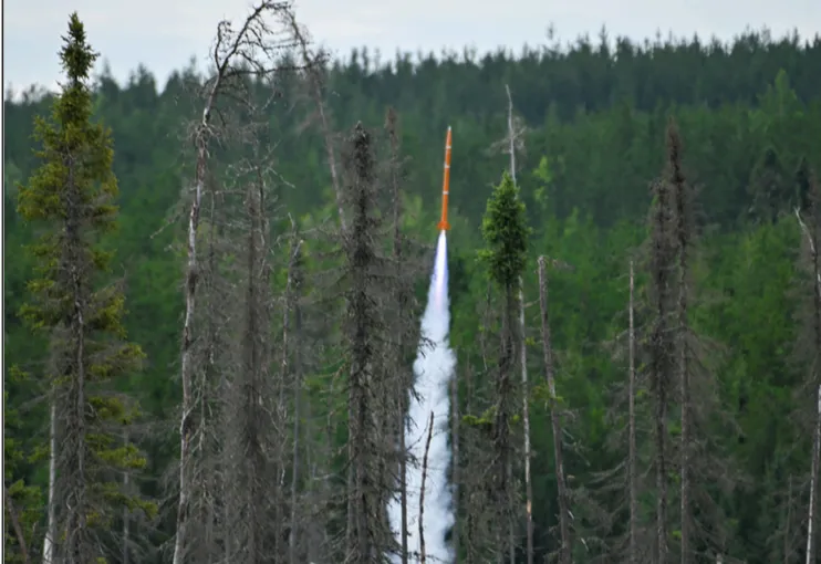 Orange Spectre rocket launched by Turner Fenton Secondary School students streaking upward through a forest clearing at Launch Canada 2025 in Timmins, Ontario.