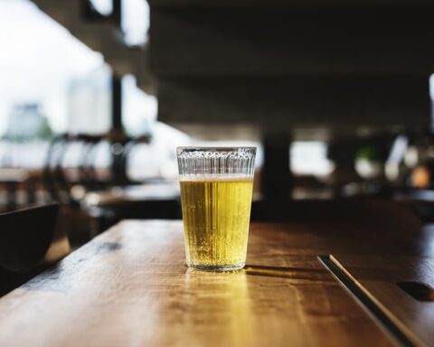 Glass of golden beer on wooden table in restaurant setting with natural lighting