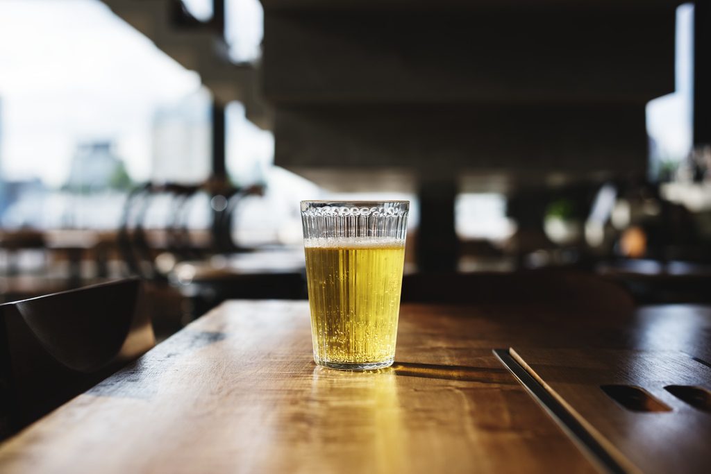 Glass of golden beer on wooden table in restaurant setting with natural lighting