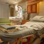 Empty hospital room with a neatly made bed, medical monitoring equipment, and basic furnishings in a VA medical facility.