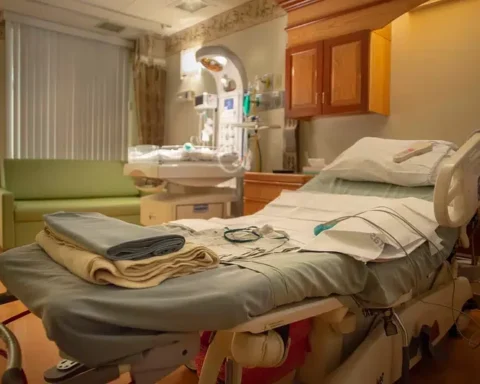 Empty hospital room with a neatly made bed, medical monitoring equipment, and basic furnishings in a VA medical facility.