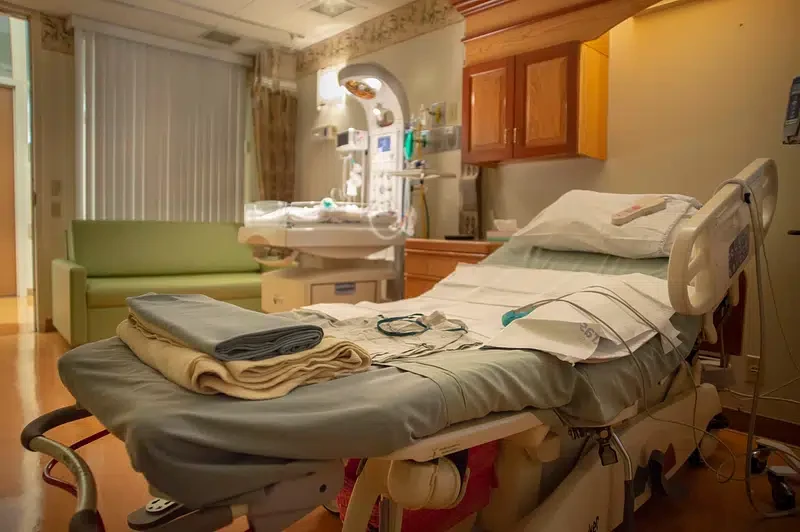 Empty hospital room with a neatly made bed, medical monitoring equipment, and basic furnishings in a VA medical facility.