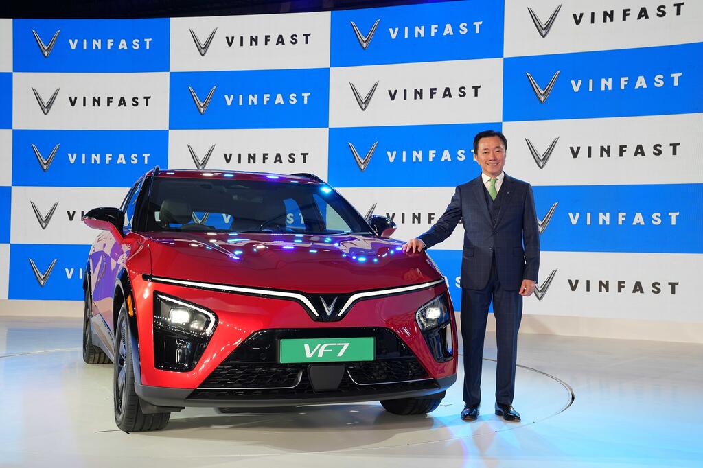 VinFast VF7 electric SUV showcased at India launch event alongside company executive, highlighting entry price of ₹20.89 lakh.