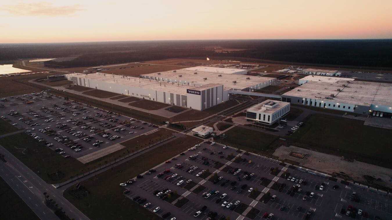 Aerial view of Volvo's Ridgeville manufacturing facility in South Carolina, showing the expansive 2.3 million square foot plant with surrounding parking lots at sunset.