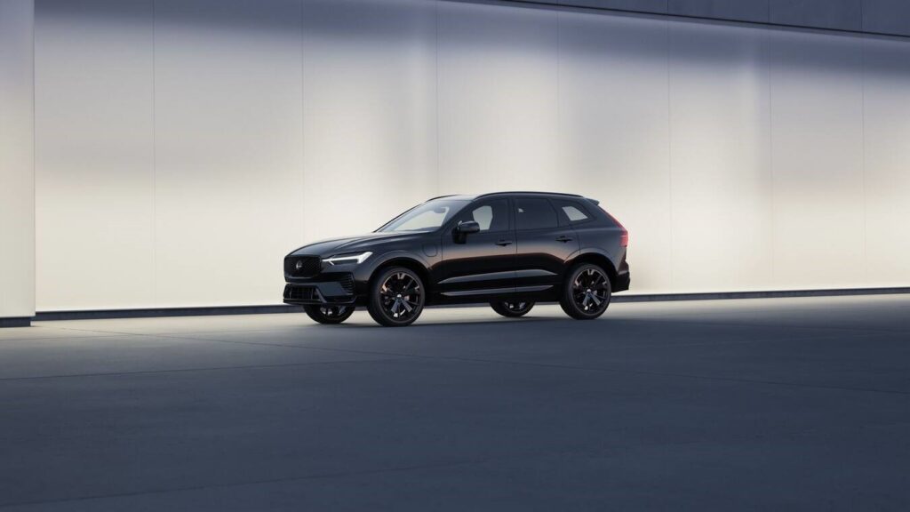 Black Volvo XC60 Black Edition SUV displayed against a minimalist light-colored backdrop, showcasing its sleek profile and distinctive black wheels.