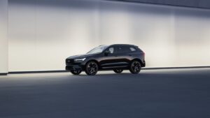 Black Volvo XC60 Black Edition SUV displayed against a minimalist light-colored backdrop, showcasing its sleek profile and distinctive black wheels.