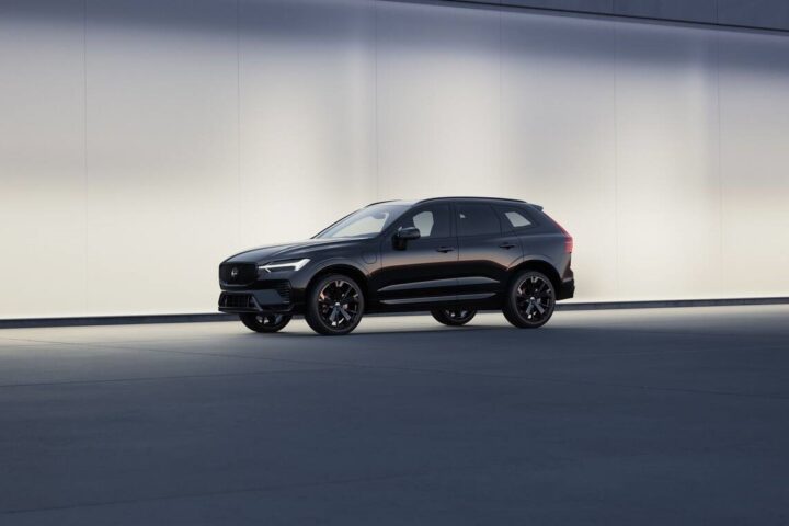 Black Volvo XC60 Black Edition SUV displayed against a minimalist light-colored backdrop, showcasing its sleek profile and distinctive black wheels.