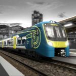 Modern blue and yellow Adessia Stream B battery-electric train with distinctive streamlined design at a station platform at night, showing the front cab and passenger cars with illuminated interior