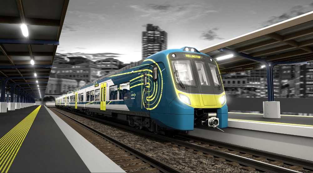 Modern blue and yellow Adessia Stream B battery-electric train with distinctive streamlined design at a station platform at night, showing the front cab and passenger cars with illuminated interior