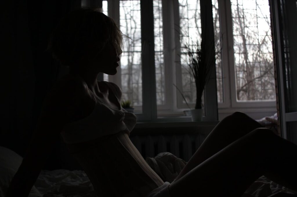 Representative Image. Silhouette of a person sitting alone by a window in dim lighting, conveying feelings of isolation and contemplation.