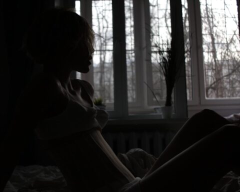 Representative Image. Silhouette of a person sitting alone by a window in dim lighting, conveying feelings of isolation and contemplation.