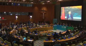 Chinese President Xi Jinping delivering a video address on screen at the United Nations Climate Summit with delegates seated in the General Assembly Hall watching.