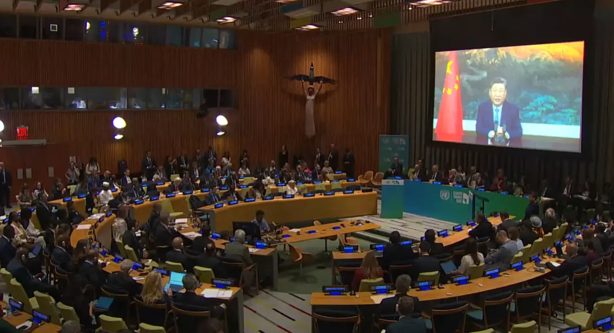 Chinese President Xi Jinping delivering a video address on screen at the United Nations Climate Summit with delegates seated in the General Assembly Hall watching.