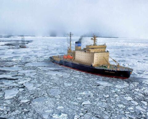 Research vessel navigating through fragmented sea ice in Antarctica, with broken ice floes surrounding the ship against a misty polar backdrop.