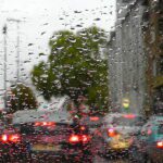 Rain on a car windshield with blurred traffic lights during wet city weather