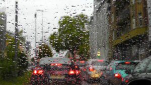 Rain on a car windshield with blurred traffic lights during wet city weather