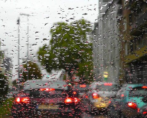 Rain on a car windshield with blurred traffic lights during wet city weather