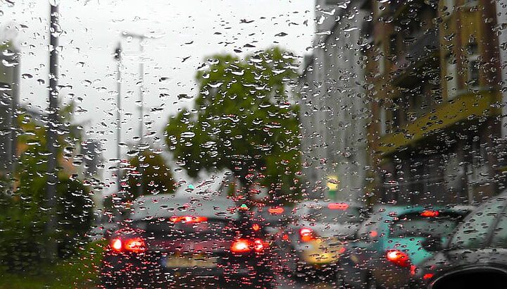 Rain on a car windshield with blurred traffic lights during wet city weather