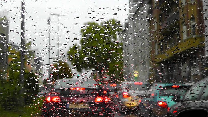 Raindrops on a windshield with blurred city tail lights during a storm