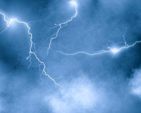 Lightning over storm clouds at night above a coastline, long exposure bolts against dark sky
