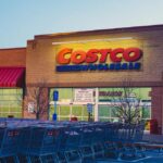 Exterior of a Costco Wholesale warehouse with customers and parked cars in front