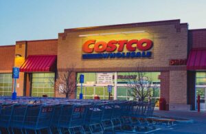 Exterior of a Costco Wholesale warehouse with customers and parked cars in front