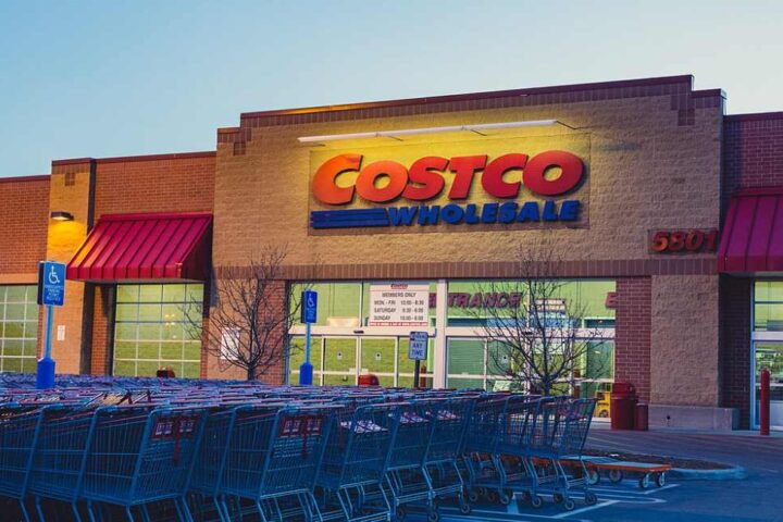 Exterior of a Costco Wholesale warehouse with customers and parked cars in front