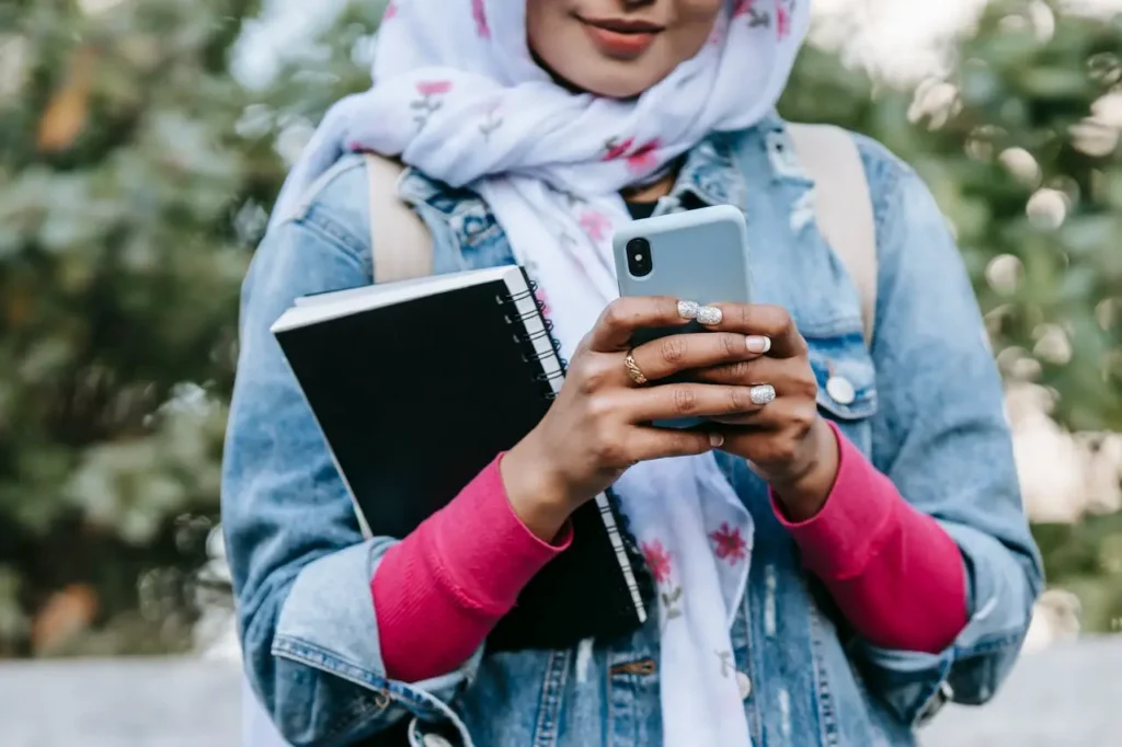 Close-up of a Muslim woman's hands holding a smartphone displaying no connection, symbolizing Afghanistan's internet shutdown.