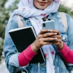 Close-up of a Muslim woman's hands holding a smartphone displaying no connection, symbolizing Afghanistan's internet shutdown.