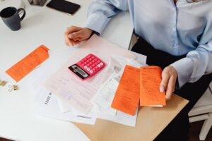 Person holding receipts and using a calculator on a desk, close-up budgeting scene