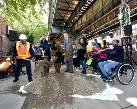 MTA officials and community members, including a person in a wheelchair, participate in the groundbreaking ceremony for the Middletown Road station accessibility project, shoveling dirt to mark the start of construction.
