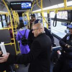 Inside an articulated MTA electric bus in New York City with passengers and police officers, part of the agency's fleet modernization efforts.