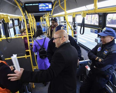 Inside an articulated MTA electric bus in New York City with passengers and police officers, part of the agency's fleet modernization efforts.