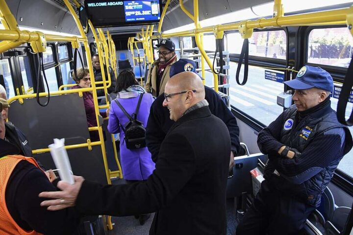 Inside an articulated MTA electric bus in New York City with passengers and police officers, part of the agency's fleet modernization efforts.