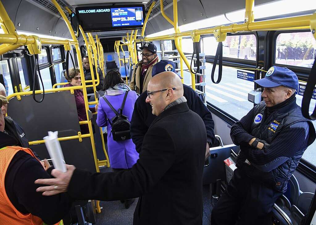 Inside an articulated MTA electric bus in New York City with passengers and police officers, part of the agency's fleet modernization efforts.