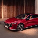 Mazda 6e electric sedan in red, three-quarter view while charging, promotional image from Mazda Australia