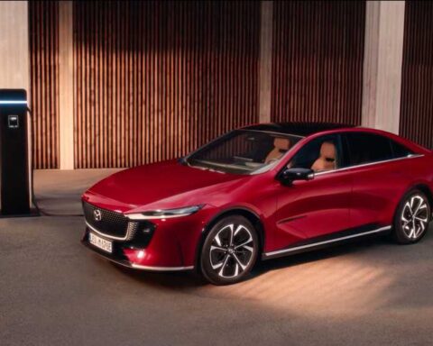 Mazda 6e electric sedan in red, three-quarter view while charging, promotional image from Mazda Australia