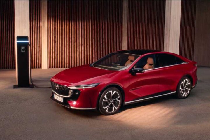Mazda 6e electric sedan in red, three-quarter view while charging, promotional image from Mazda Australia