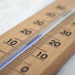 Close-up of a wooden Celsius thermometer with blue liquid column and shallow depth of field.