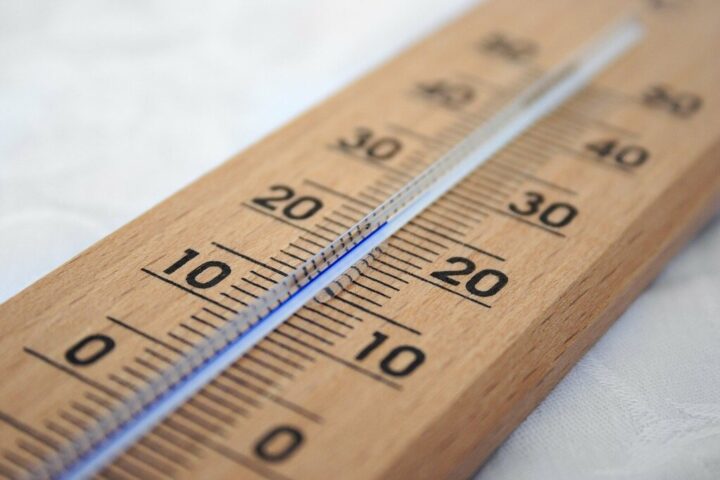 Close-up of a wooden Celsius thermometer with blue liquid column and shallow depth of field.