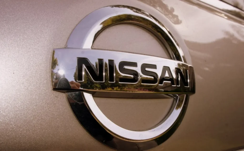 Nissan silver logo emblem on a vehicle with metallic finish background