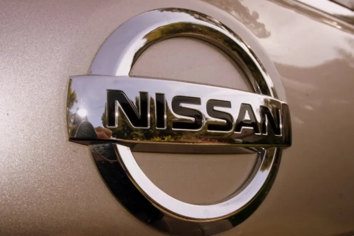 Nissan silver logo emblem on a vehicle with metallic finish background