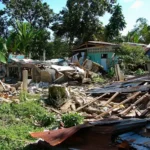 Collapsed home and debris in Loon, Bohol, Philippines after a strong quake, with nearby houses and trees in daylight