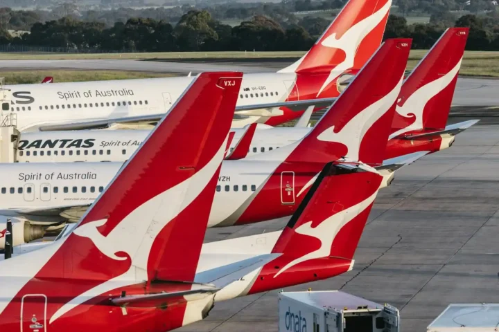 Multiple Qantas aircraft tails at Melbourne Airport with red kangaroo livery, parked on the tarmac in daylight