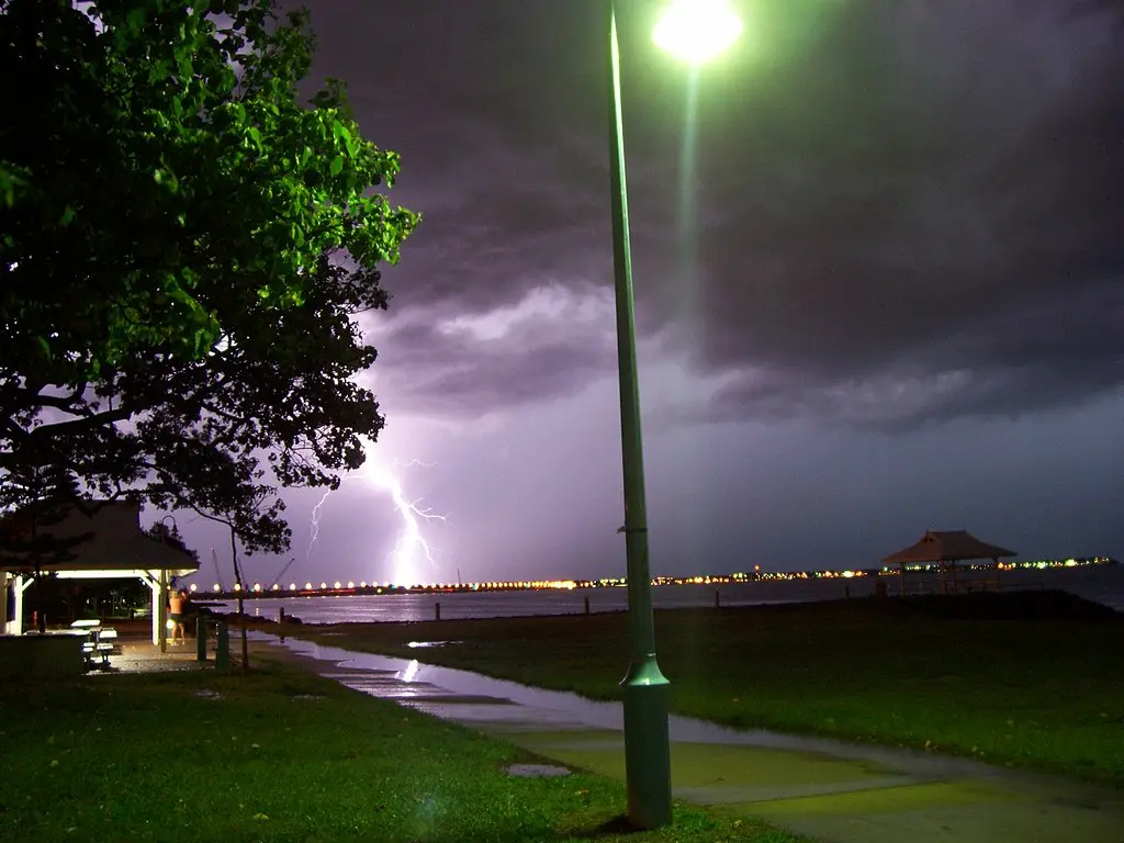 View of Brighton towards Redcliffe during a thunderstorm in Queensland, Australia, showing dark storm clouds gathering over the illuminated coastline at night.