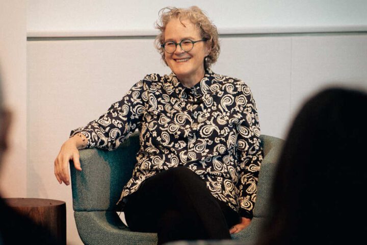 Dr. Jeanne Marrazzo smiling while seated in a blue chair, wearing a black and white patterned blouse during what appears to be an interview or presentation at NIAID.