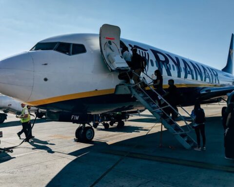 Ryanair Boeing 737 aircraft parked at an airport with passengers boarding via stairs, ground crew visible on tarmac